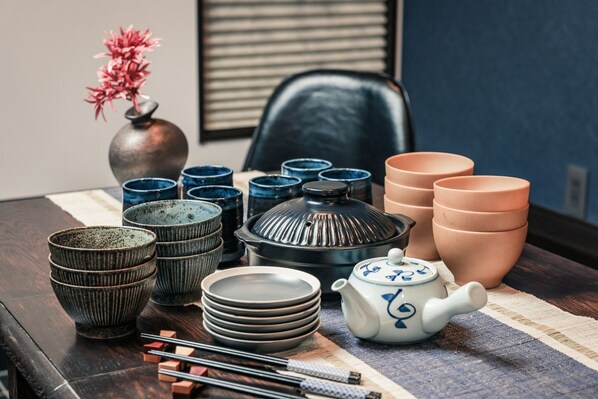 A dining table with various ceramic dishes, a teapot, and chopsticks.