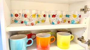 Un estante con tazas de vidrio y cerámica de colores.