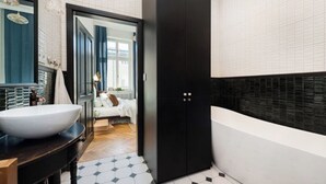 A modern bathroom with a large white sink, a black cabinet, and a black and white tiled floor.