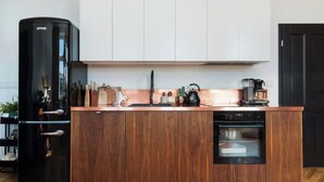 A modern kitchen with wooden cabinets, a black refrigerator, and a built-in oven.