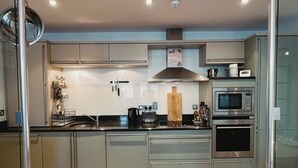 Une cuisine moderne dotée d’appareils électroménagers en acier inoxydable, d’un plancher en bois et d’un îlot central.
