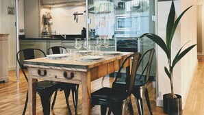 Un coin repas avec une table et des chaises en bois, une plante en pot et une cuisine en arrière-plan.