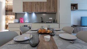 Una cocina moderna con armarios de madera, horno empotrado y un comedor con mesa para dos.