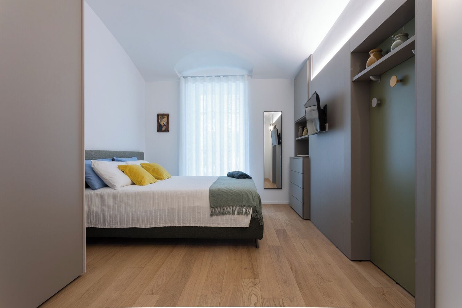 A modern bedroom with a bed, bedside table, and a wardrobe.