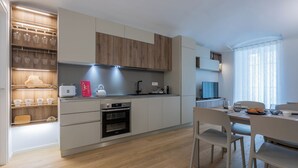 Una cocina moderna con armarios de madera, horno empotrado y comedor con mesa y sillas.