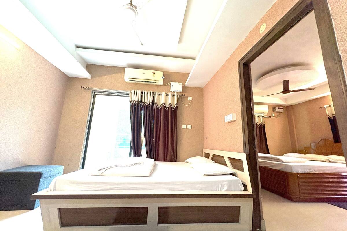 Habitación de hotel con cama, ventilador de techo, equipo de aire acondicionado y un espejo grande.