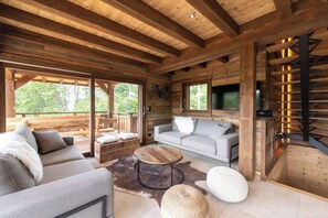L’intérieur d’un chalet confortable, avec un canapé, une table basse ronde et une cheminée.