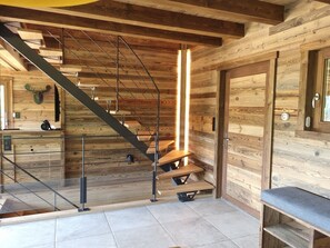Un intérieur en bois avec un escalier, un banc et une porte.