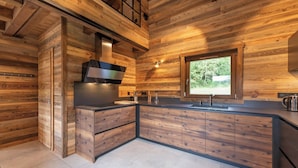 A modern kitchen with wooden cabinetry, a built-in stove, and a window providing natural light. - ✨ Chalet Atlas – Hot Tub, Sauna & 500m from the Slopes (Gérardmer)