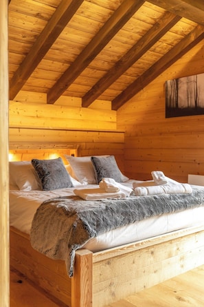 Ein Schlafzimmer in einer Holzhütte mit einem Bett, Kissen und einer Decke.