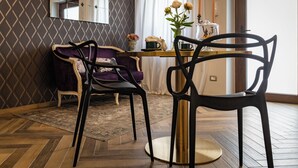 Un comedor con una mesa, sillas, un florero con flores y velas.