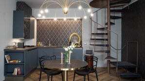 Una cocina moderna con una isla integrada, una mesa redonda de comedor con sillas y una escalera de caracol.