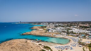 Luftaufnahme einer Küstenstadt mit Strand, Hotels und blauem Meer.