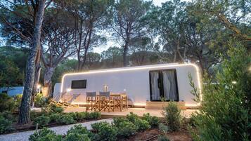 Una caravana moderna con porche cubierto, zona de estar exterior y jardín.