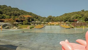 Una piscina con cubierta de madera, un tobogán y un flotador inflable grande.