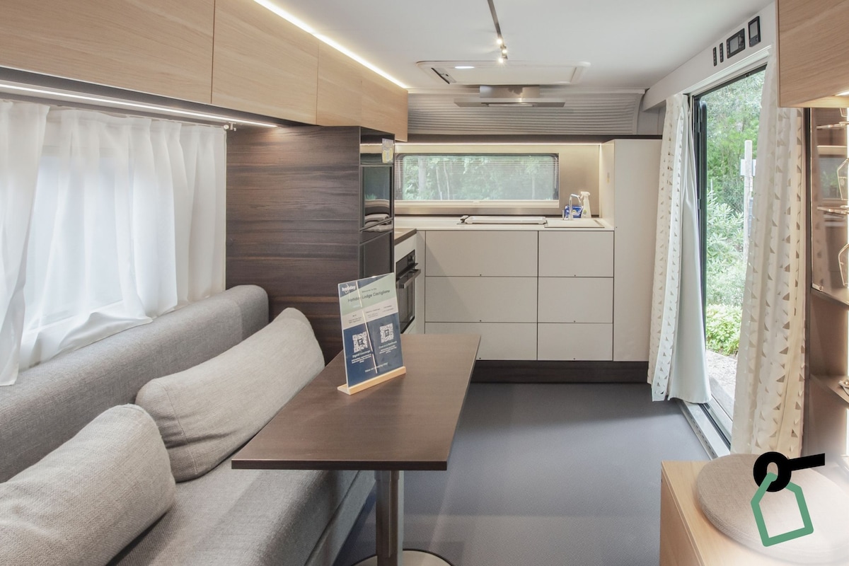 Una kitchenette compacta con una ventana, un sofá y una mesa con un letrero.