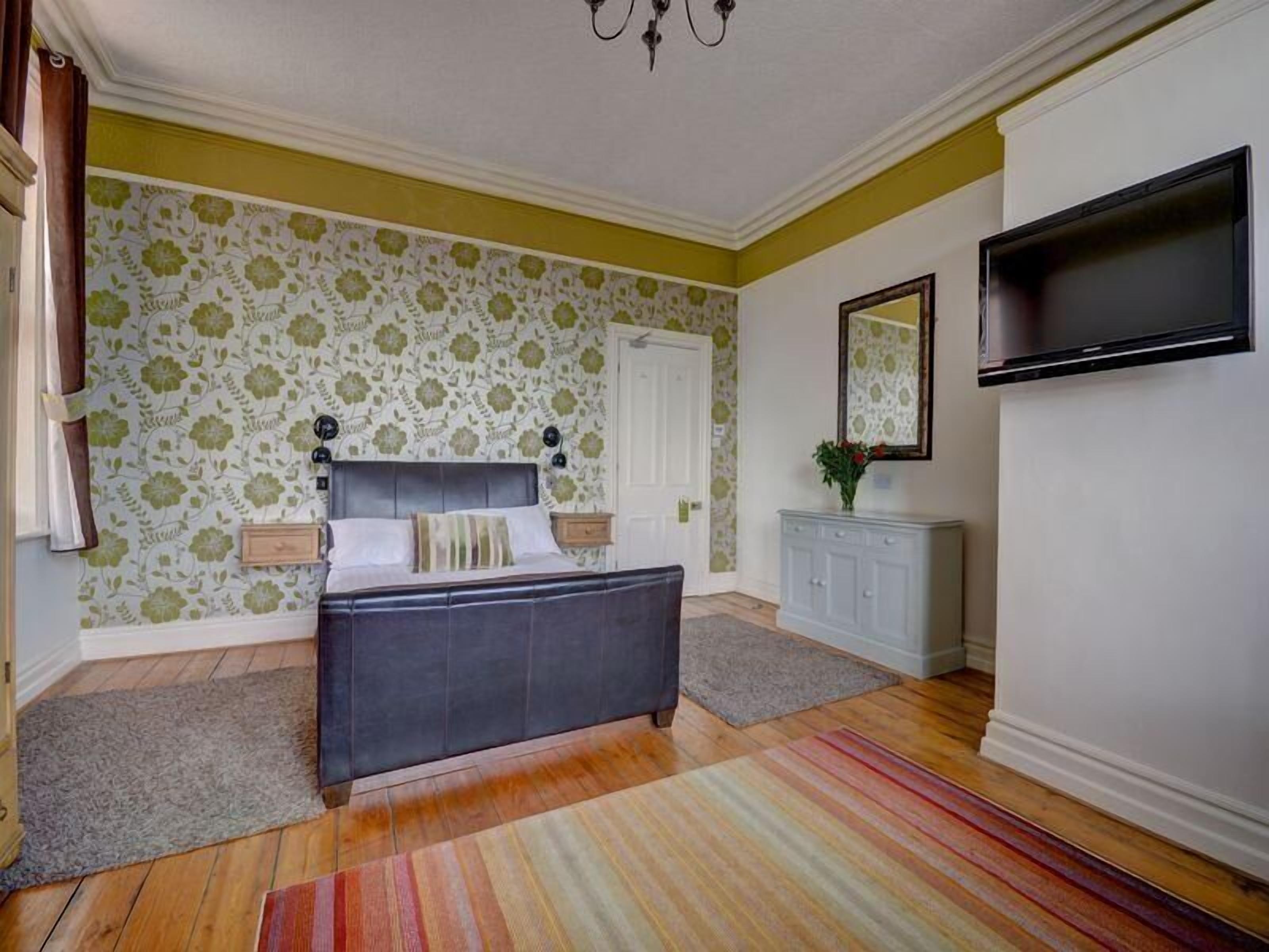 Une chambre à coucher avec un lit, une commode, un téléviseur et une porte.