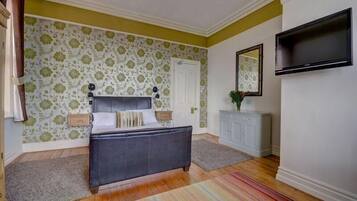 Une chambre à coucher avec un lit, une commode, un téléviseur et une porte.