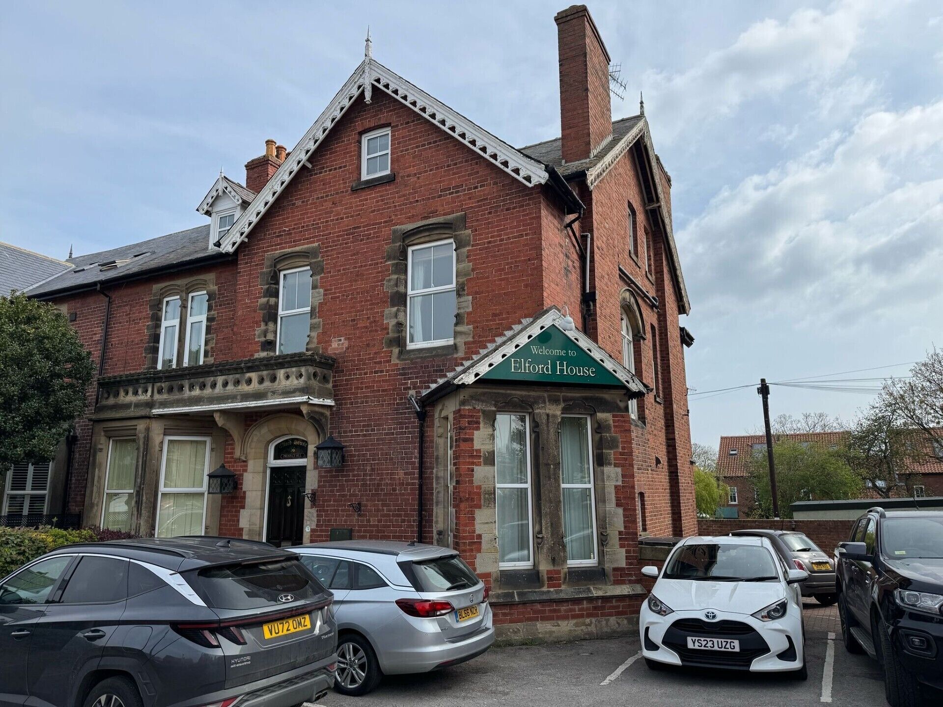 A red brick building with a green awning that reads "Welcome to Elford House."