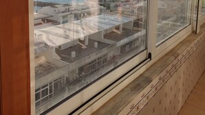 Une fenêtre donnant sur une zone côtière, avec vue sur des bâtiments et une étendue d’eau.