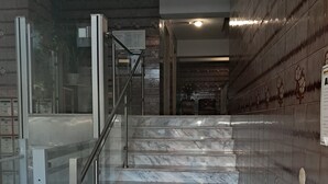 Un escalier en marbre avec des rampes en verre menant à un ascenseur.