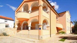 Un edificio a due piani con un balcone, un vialetto in pietra e un piccolo giardino.