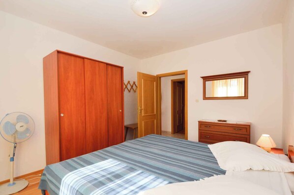 A bedroom with a bed, a wooden wardrobe, a bedside table with a lamp, and a wall-mounted mirror. - Apartments in Vinkuran/istrien 11042 (Medulin)