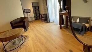 Een woonkamer met een bank, een rond bijzettafeltje, een televisie en een bed.