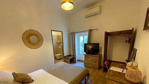 Een hotelkamer met een bed, een televisie, een dressoir, een spiegel en een raam.