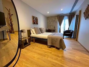 A bedroom with a bed, a chair, a desk, and a television.