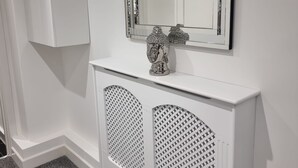 A white console table with a decorative item and a mirror above it. - London Oasis Modern 2BR Apartment (London)