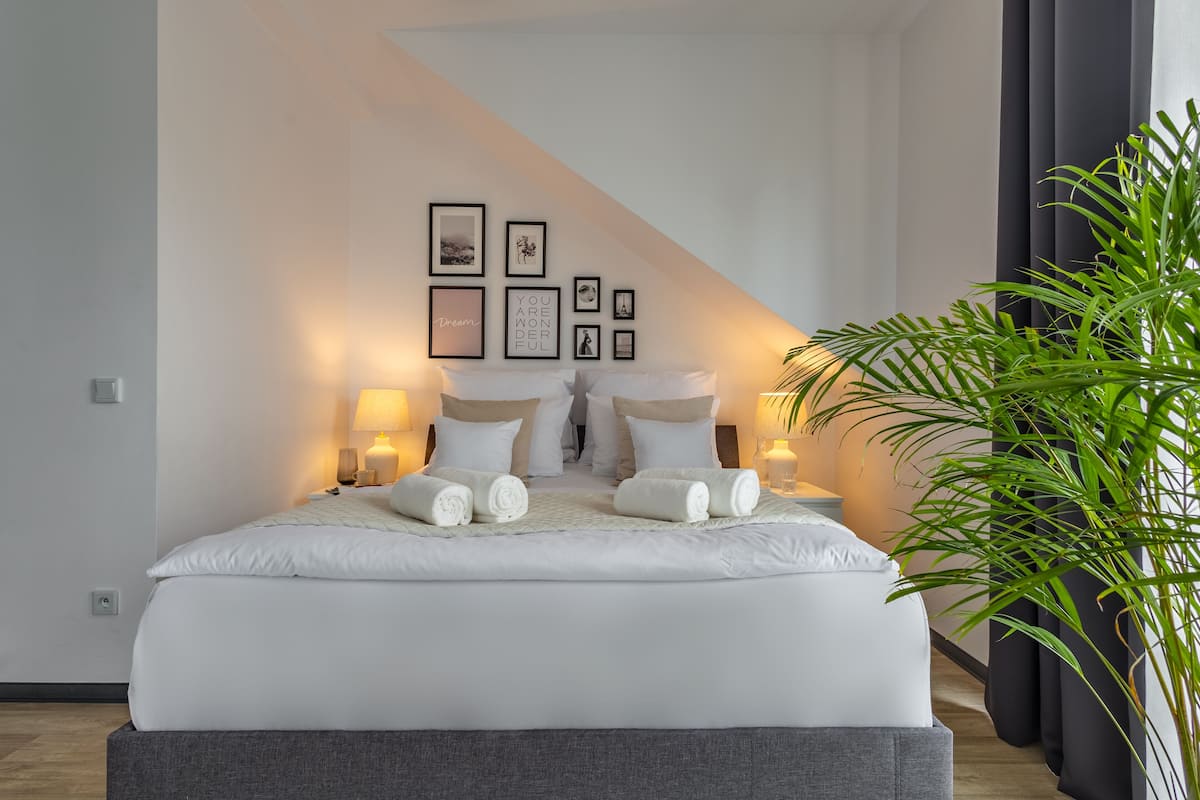 Un dormitorio moderno con una cama grande, cuadros enmarcados en la pared y una planta en maceta.