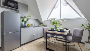 Una cocina moderna con microondas integrado, refrigerador de doble puerta y un comedor con mesa y sillas.