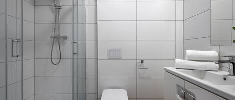 A modern bathroom with a glass-enclosed shower, a white toilet, and a sink with a mirror.