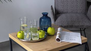 A wooden table with a glass pitcher, two glasses, and two apples.