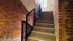 A staircase with a black metal railing, leading up to a landing with a window. - Tkalnia Snu (Lódz)