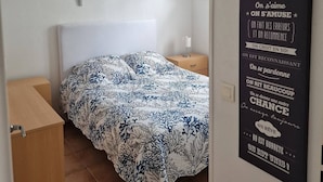 Ett sovrum med en säng, ett nattduksbord, en väggmonterad lampa och ett inspirerande citat på väggen.