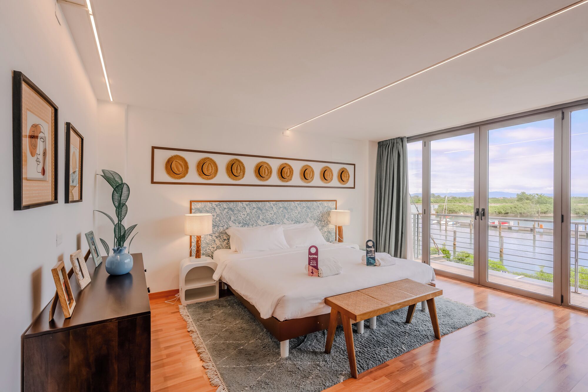 A modern hotel room with a large bed, a view of the outdoors, and a balcony.