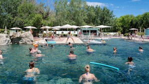A swimming pool area with clear water, lounge chairs, umbrellas, and a shaded seating area. - Hotiday Grado Marina (Grado)