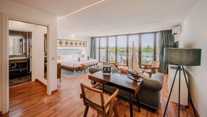 A modern hotel room with a bed, desk, chairs, a large window with a view, and a wardrobe. - Hotiday Grado Marina (Grado)