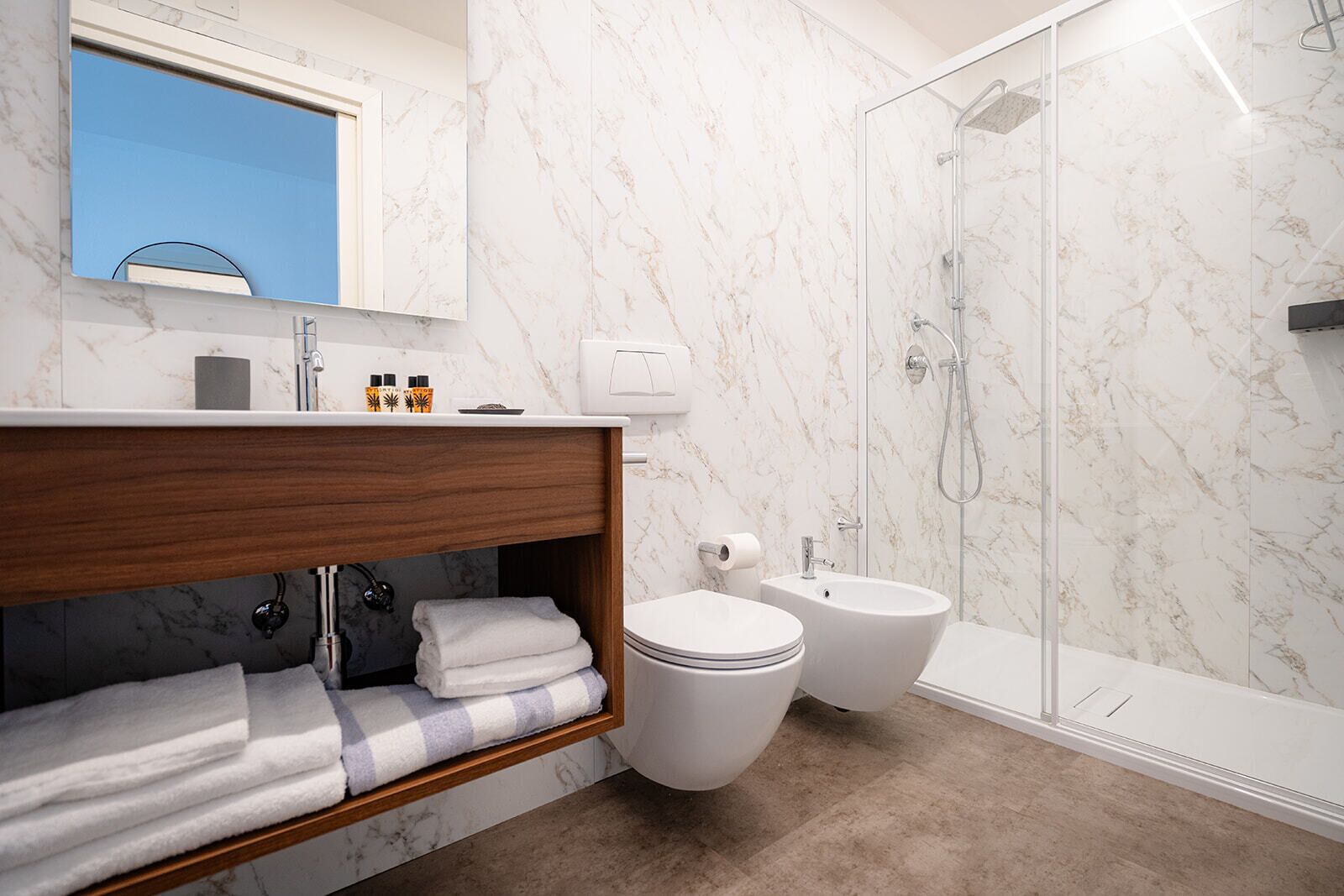 Un baño moderno con ducha de mármol, inodoro y bidé.