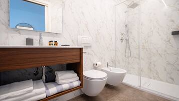 Un baño moderno con ducha de mármol, inodoro y bidé.