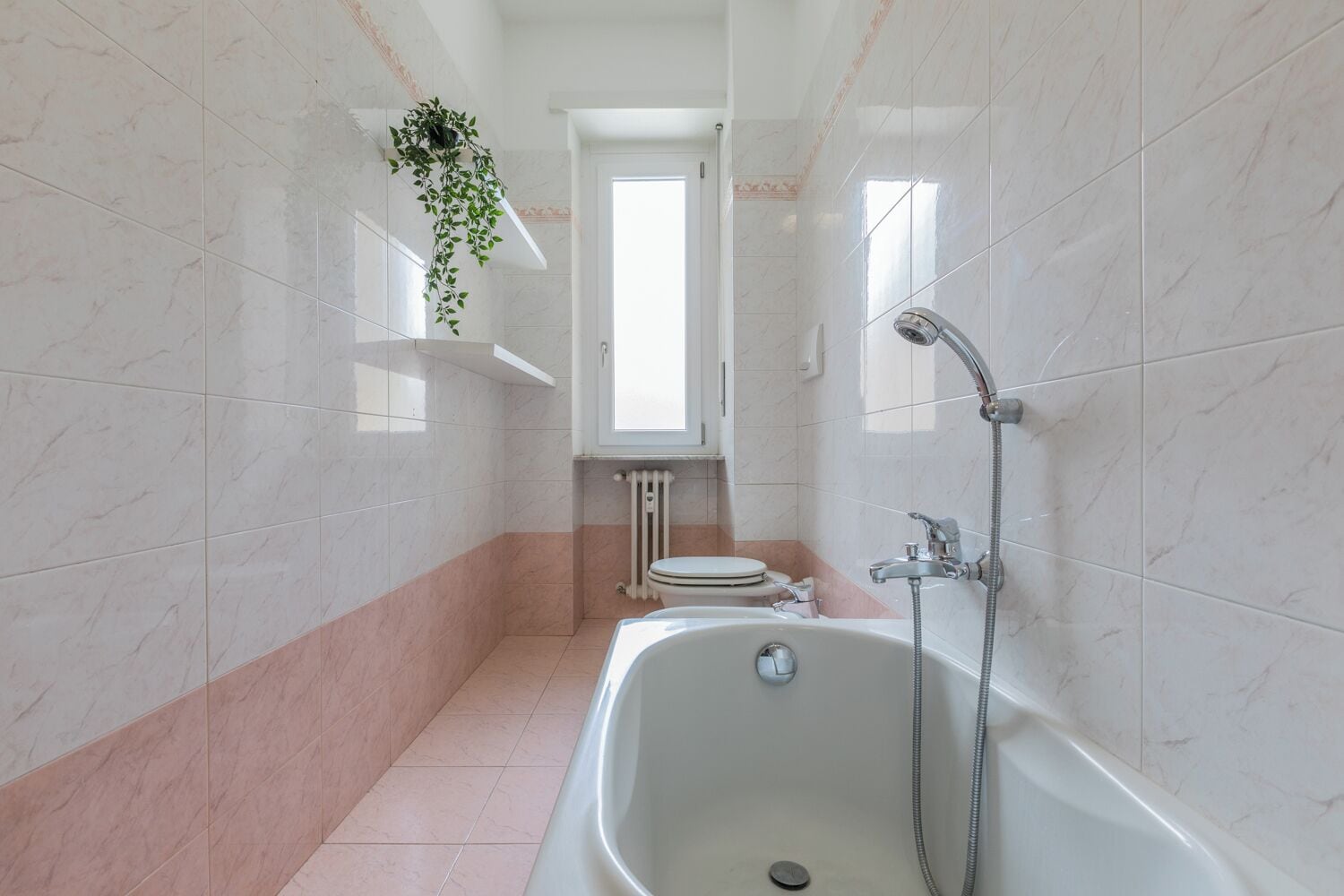 Ein Badezimmer mit Badewanne, Toilette und einem Fenster.