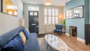 A living room with a sofa, a coffee table, a chair, a fireplace, and a large mirror. - Beautiful 2bed Central Home (Cambridge)