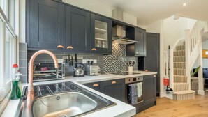 A modern kitchen with dark cabinetry, a stainless steel sink, and a built-in oven. - Beautiful 2bed Central Home (Cambridge)