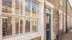 A townhouse with a white-framed window, a dark blue door, and a brick facade. - Beautiful 2bed Central Home (Cambridge)