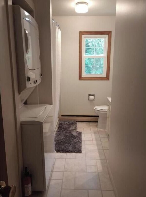 Ein schmales Badezimmer mit Toilette, Waschbecken und einem Fenster.