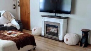 A living room with a fireplace, a television mounted on the wall, a sofa, and two large bean bags.