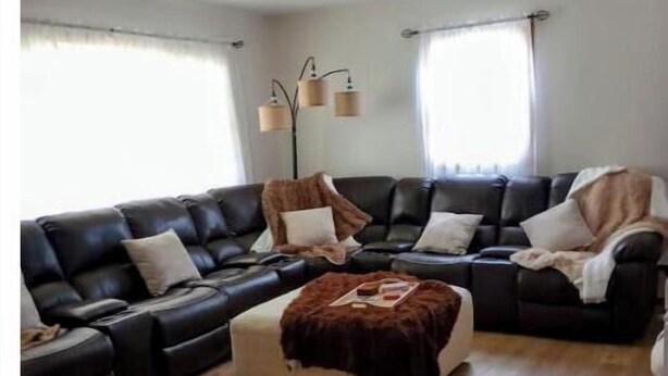 A modern living room with a sectional sofa, a small ottoman, and a floor lamp.