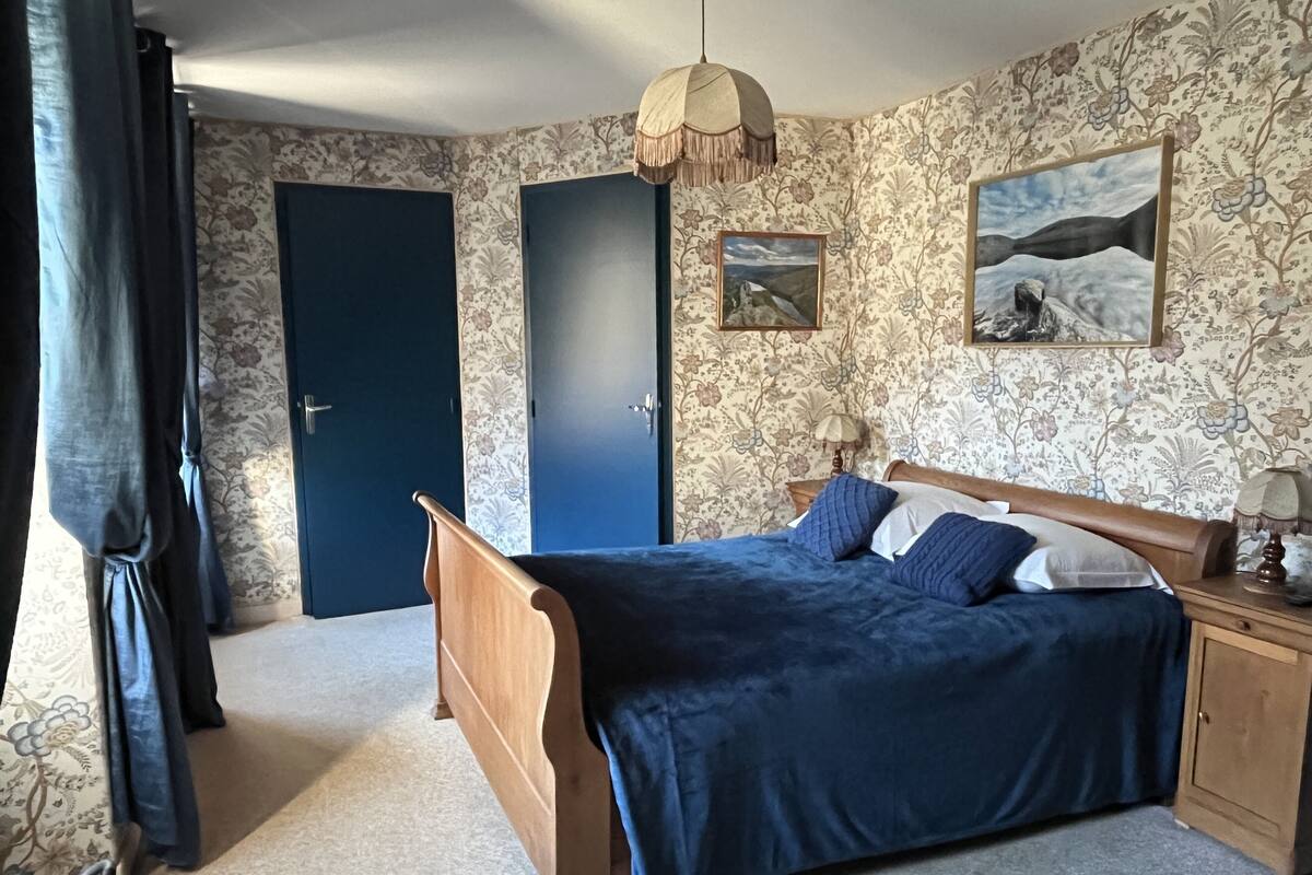 Un dormitorio con cama de madera, una mesita de noche, una lámpara y un cuadro en la pared.